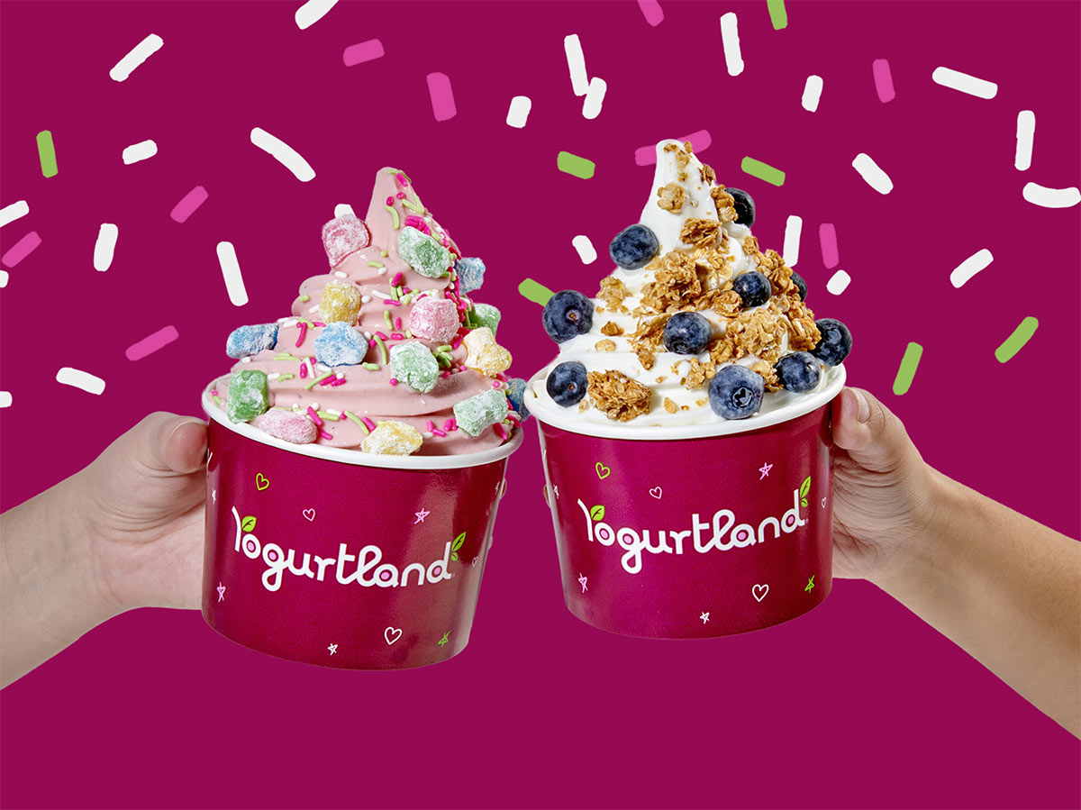Two Yogurtland frozen yogurt cups with a variety of toppings